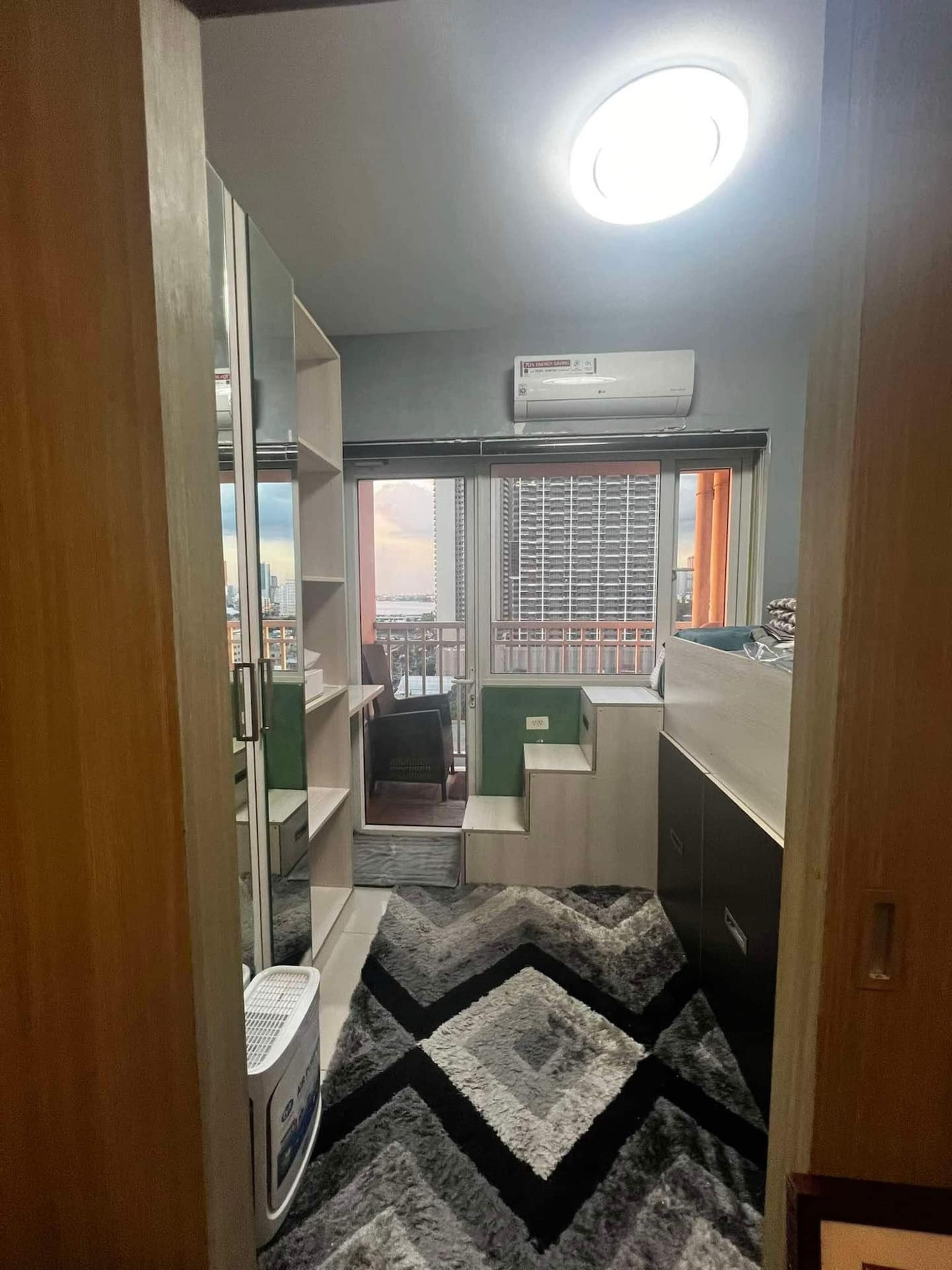 A compact kitchen with a built-in stove, a window with blinds, and a view of the cityscape.