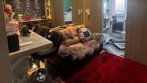 A modern living room with a sofa, a dining area with a table, and a large window offering a view of the city. - Breeze Residences Condos (Pasay)