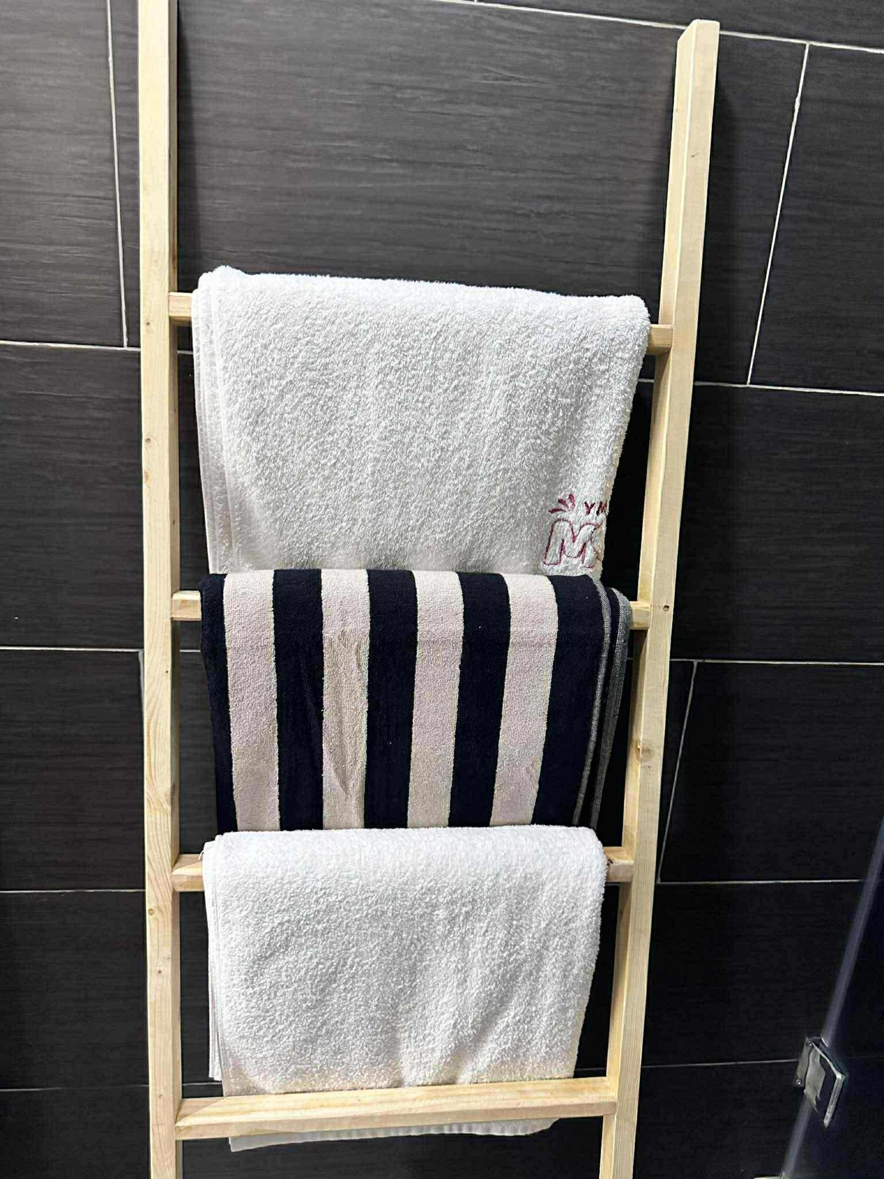 Ein hölzerner Handtuchhalter mit drei Handtüchern.