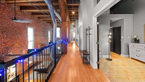 A spacious hallway with exposed brick walls, wooden beams, and a wooden floor. - Two Story Penthouse - Walk to the Convention Ctr (Indianapolis)