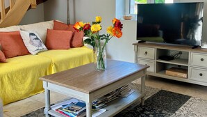 A living room with a yellow sofa, a coffee table, a TV, and a vase with flowers. - The maples - sainte maure de Touraine (Sainte-Maure-de-Touraine)