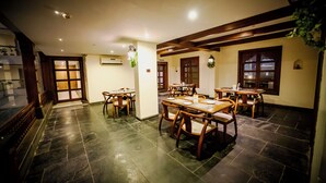 A restaurant with multiple tables and chairs, a staircase, and a wooden ceiling. - The Sky Court - An Hospitality (Chhatrapati Sambhajinagar)