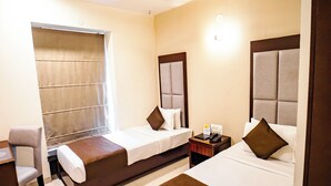 A hotel room with two beds, a desk, and a window with curtains. - The Sky Court - An Hospitality (Chhatrapati Sambhajinagar)