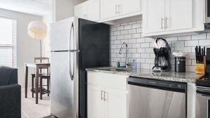 Een moderne keuken met roestvrijstalen apparatuur, witte kastjes en een granieten aanrecht.