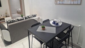 A modern dining area with a table, chairs, and a painting on the wall. - N&S Fms, Cozy two bedroom apartment close to Fleming Metro station (Thessaloniki)