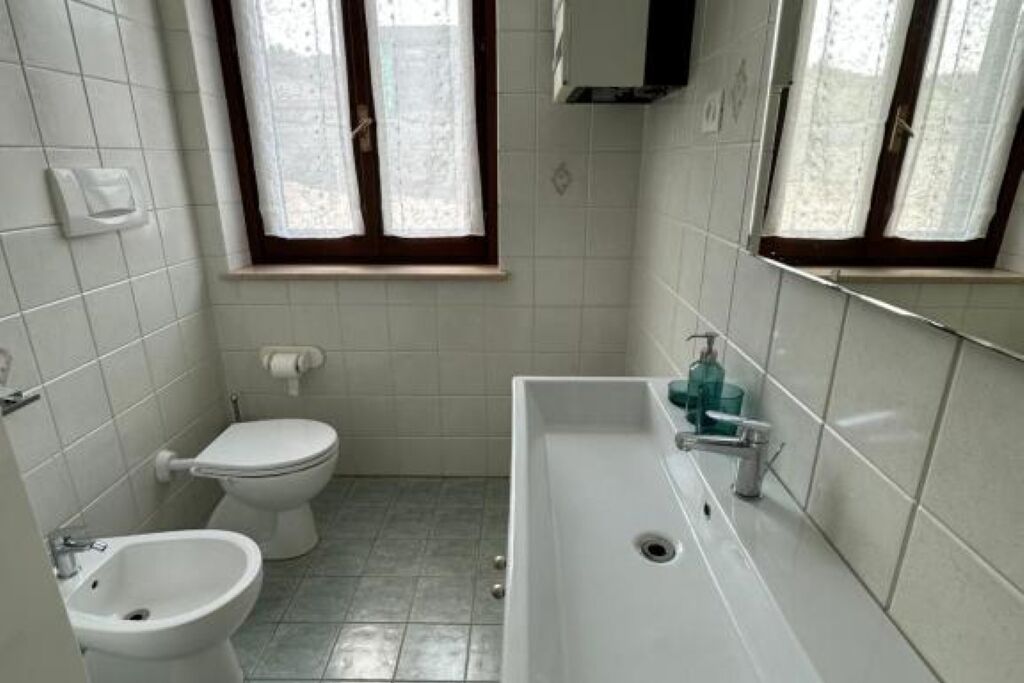 Et badeværelse med toilet, bidet og en vask med spejl.