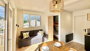 A modern apartment with a dining area, sofa, and built-in storage. - New apartment for 6 people - close to the city center (Bagnères de Luchon)