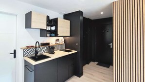 A compact kitchen with a black countertop, a sink, and a black cabinet. - New apartment for 6 people - close to the city center (Bagnères de Luchon)