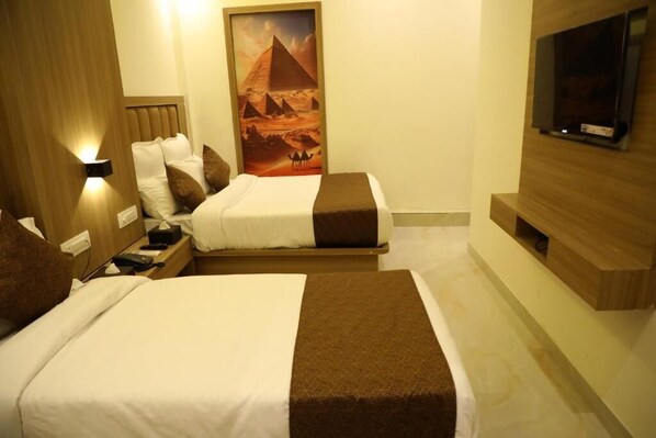 A hotel room with two beds, a TV mounted on the wall, and a poster of the pyramids. - Hotel Bellamont (Mumbai)