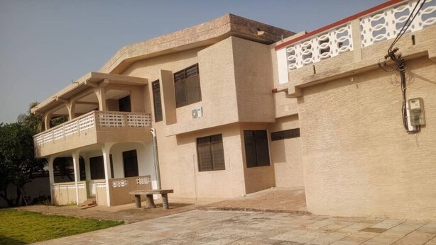 A two-story building with a balcony on the ground floor and a flat roof. - Enyo Home (Tema)