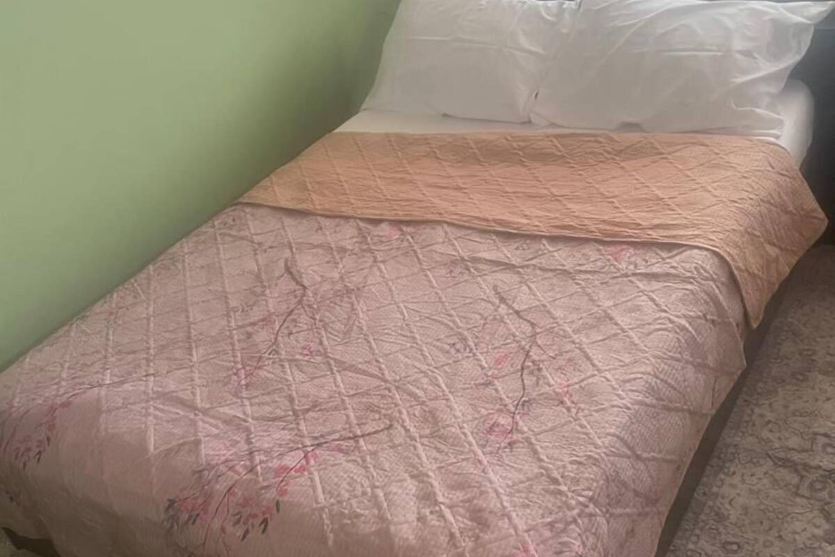 A bed with a floral-patterned bedspread, a white pillow, and a beige blanket.
