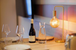 Ein Esstisch, gedeckt mit Weingläsern, einer Weinflasche, einer Karaffe und einer Lampe.