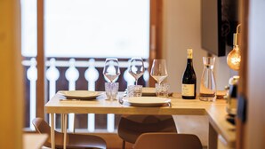A dining table set with wine glasses, a bottle, and a candle, with chairs around it.