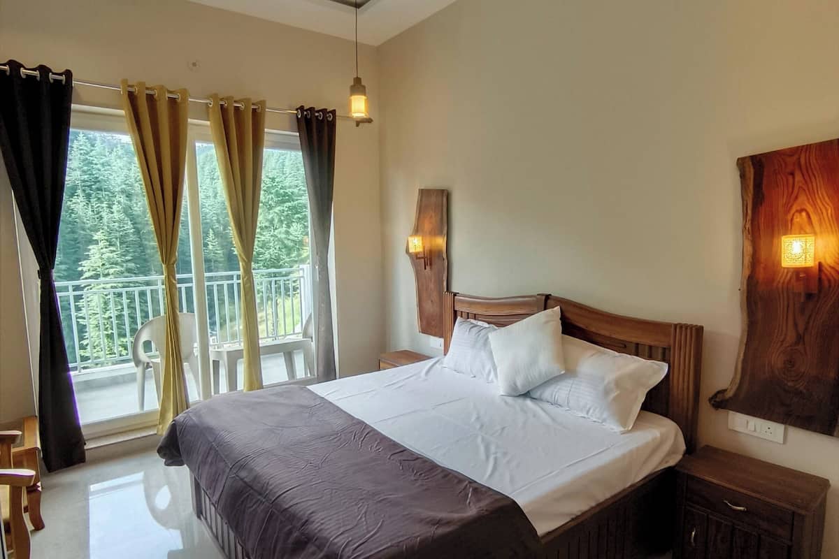 A bedroom with a large bed, a ceiling fan, a nightstand, and a view of the outdoors.