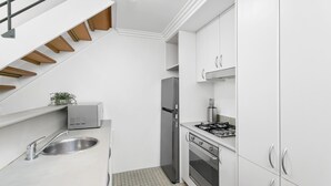 A modern kitchen with white cabinets, a stainless steel sink, a built-in oven, and a gas stove.