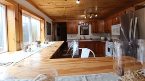 Una cocina con armarios de madera, un refrigerador de acero inoxidable y una mesa de comedor con sillas.
