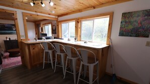 Una cocina con isla de madera, taburetes de bar y ventanas amplias.