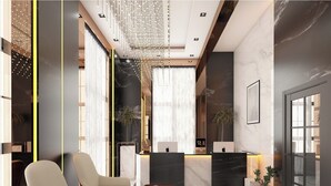 Un espace d’accueil moderne avec deux fauteuils en cuir, un comptoir d’accueil en marbre et un lustre.
