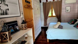 A bedroom with a bed, a wooden dresser, a framed picture, and a small table with a lantern. - gites o fil de l'eau (Omessa)