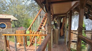 A wooden deck with a staircase leading to a covered area, surrounded by a wooden fence and trees. - gites o fil de l'eau (Omessa)