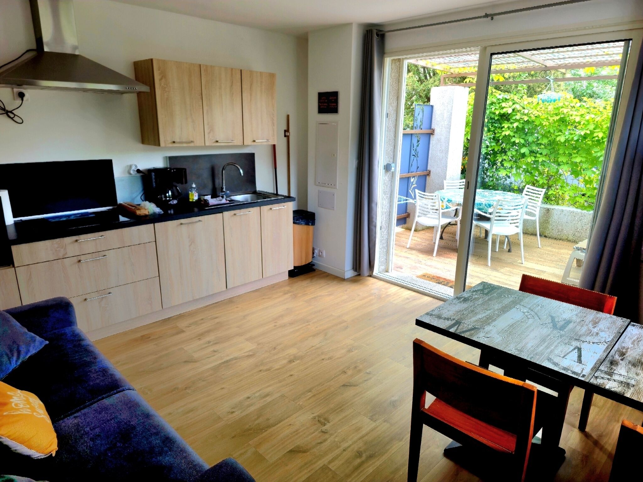 A compact living space with a kitchenette, a dining area, and a sliding glass door leading to an outdoor patio.