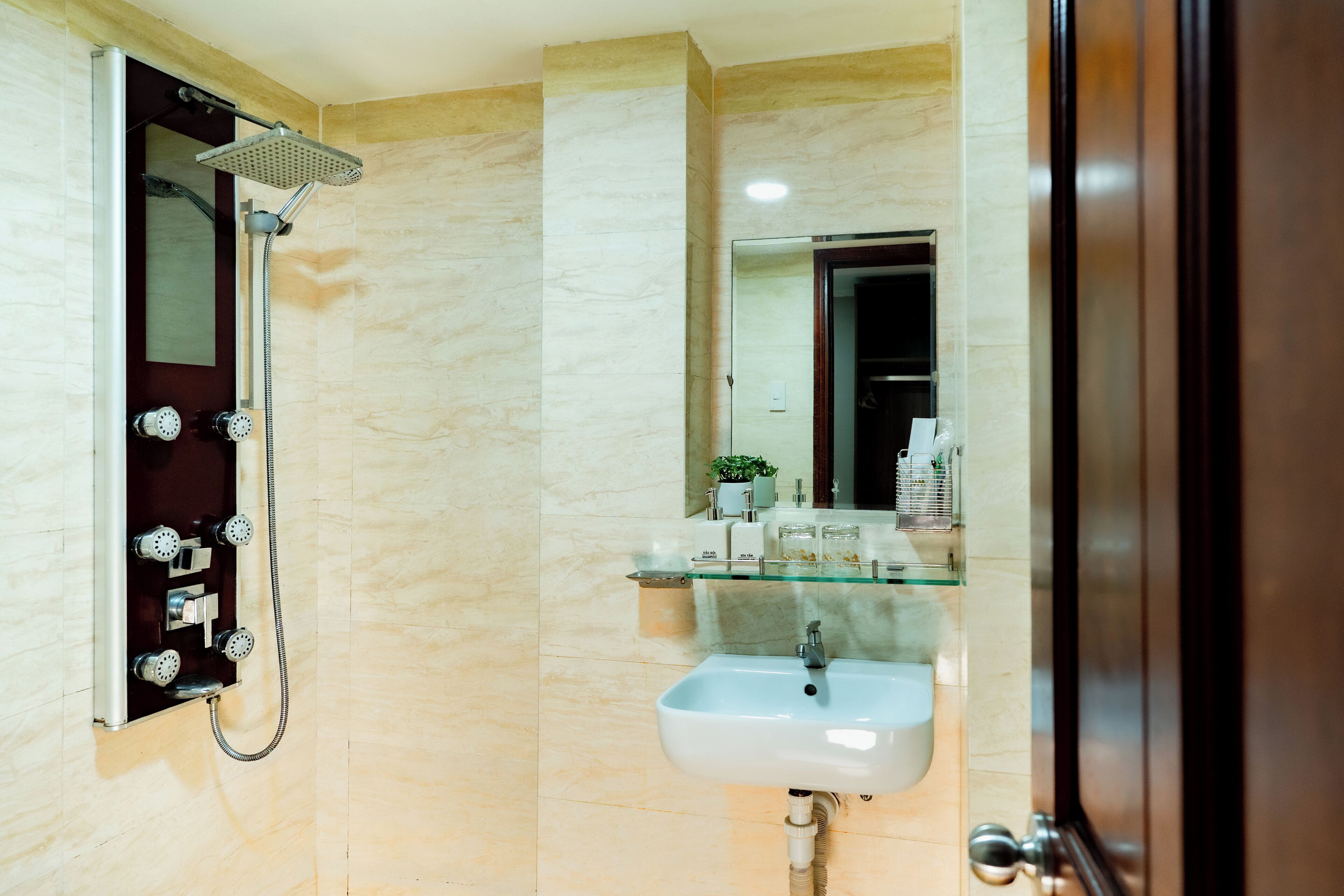 A bathroom with a glass shower enclosure, a sink, and a mirror.