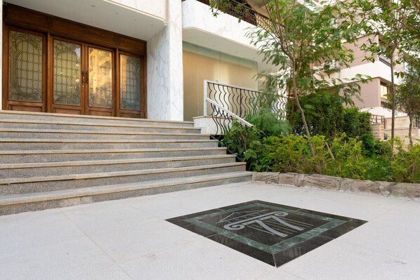 A building entrance with a set of stone steps leading to a wooden door with glass panels.