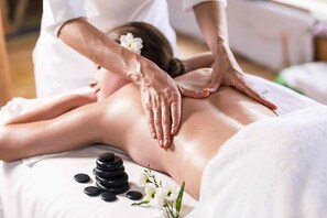 A massage therapy session with a person lying face down on a massage table, receiving a back massage.