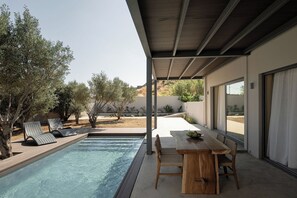 A poolside area with lounge chairs, a wooden table, and a view of the surrounding landscape. - Mitos Ultimate Escape Villa (Naxos)