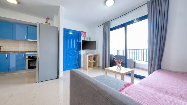 A modern room with a kitchenette, a sofa, a TV, and a balcony with a view. - El rincón de famara - By LVH (Famara)