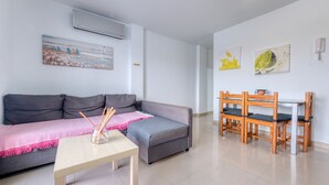 A modern living room with a grey sofa, a wooden coffee table, and a dining area with wooden chairs. - El rincón de famara - By LVH (Famara)