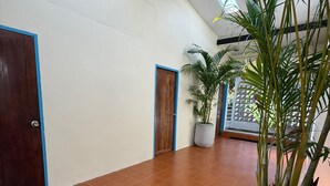 A hallway with tiled flooring, wooden doors, and potted plants. - Baan Hinlad Home and Hostel (Koh Samui)