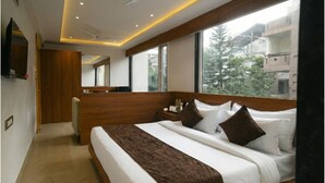 Een moderne hotelkamer met een groot bed, een houten hoofdbord en uitzicht op buiten.