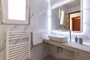 A bathroom with a white marble sink, a towel rack, and a large mirror.