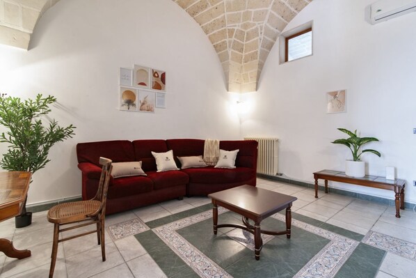 A living room with a red sofa, wooden coffee table, and a patterned rug.