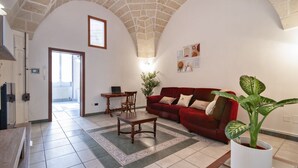 A living room with a red sofa, a wooden coffee table, and a potted plant. - Sardinia 10 - Lecce Selection (Lecce)