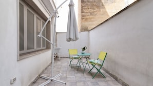 A small patio area with a table and chairs, a floor lamp, and a window with blinds. - Sardinia 10 - Lecce Selection (Lecce)