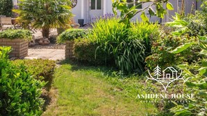 Una casa con jardín, una palmera y diversas plantas.
