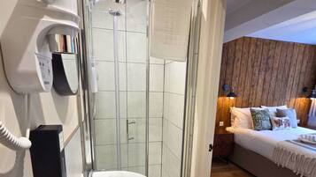 Une salle de bain moderne avec une douche à parois de verre, un lavabo blanc et un sèche-cheveux fixé au mur.