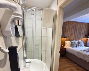 A modern bathroom with a glass shower enclosure, a white sink, and a hairdryer on the wall.