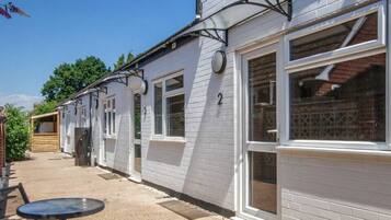 A row of white buildings with numbered windows, outdoor seating, and a logo for Ashdene House.