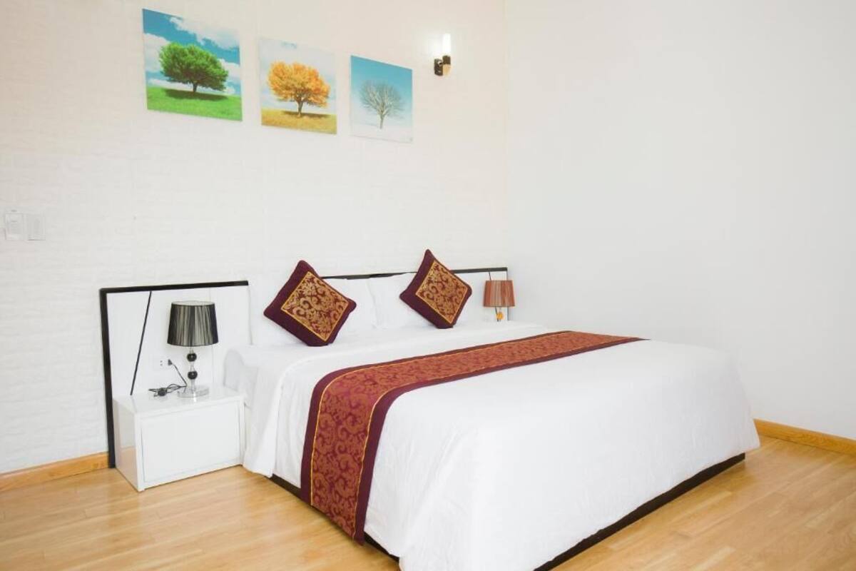 A bedroom with a bed, nightstand, lamp, and wall art.