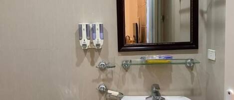 A small, modern bathroom with a white sink, a mirror, and a toilet.
