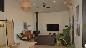 Een moderne woonkamer met een bank, een eettafel met een schaal, een open haard en een opgehangen hertenkop.