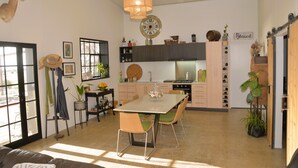 Een moderne keuken met een eethoek, met een grote klok, een kroonluchter en diverse keukenapparaten.