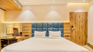Uma cama grande com cabeceira de madeira, uma porta de madeira e uma pequena mesa com uma cadeira.