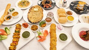 Diversos pratos indianos, incluindo naan, samosas e um prato de frango tandoori.