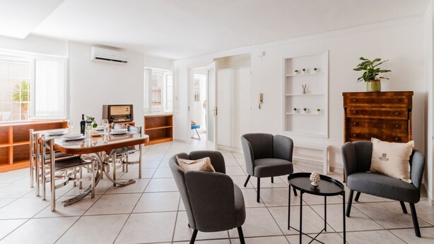 A spacious living area with a dining table, chairs, and a coffee table. There is a bookshelf and a plant on a wooden cabinet. - Studio Anid - Lecce Selection (Lecce)