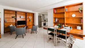 A modern living room with a TV, seating, and a dining area with a table set for four. - Studio Anid - Lecce Selection (Lecce)