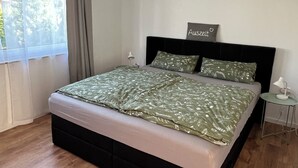 Moderni makuuhuone, jossa on suuri sänky, yöpöytä ja pieni sivupöytä.